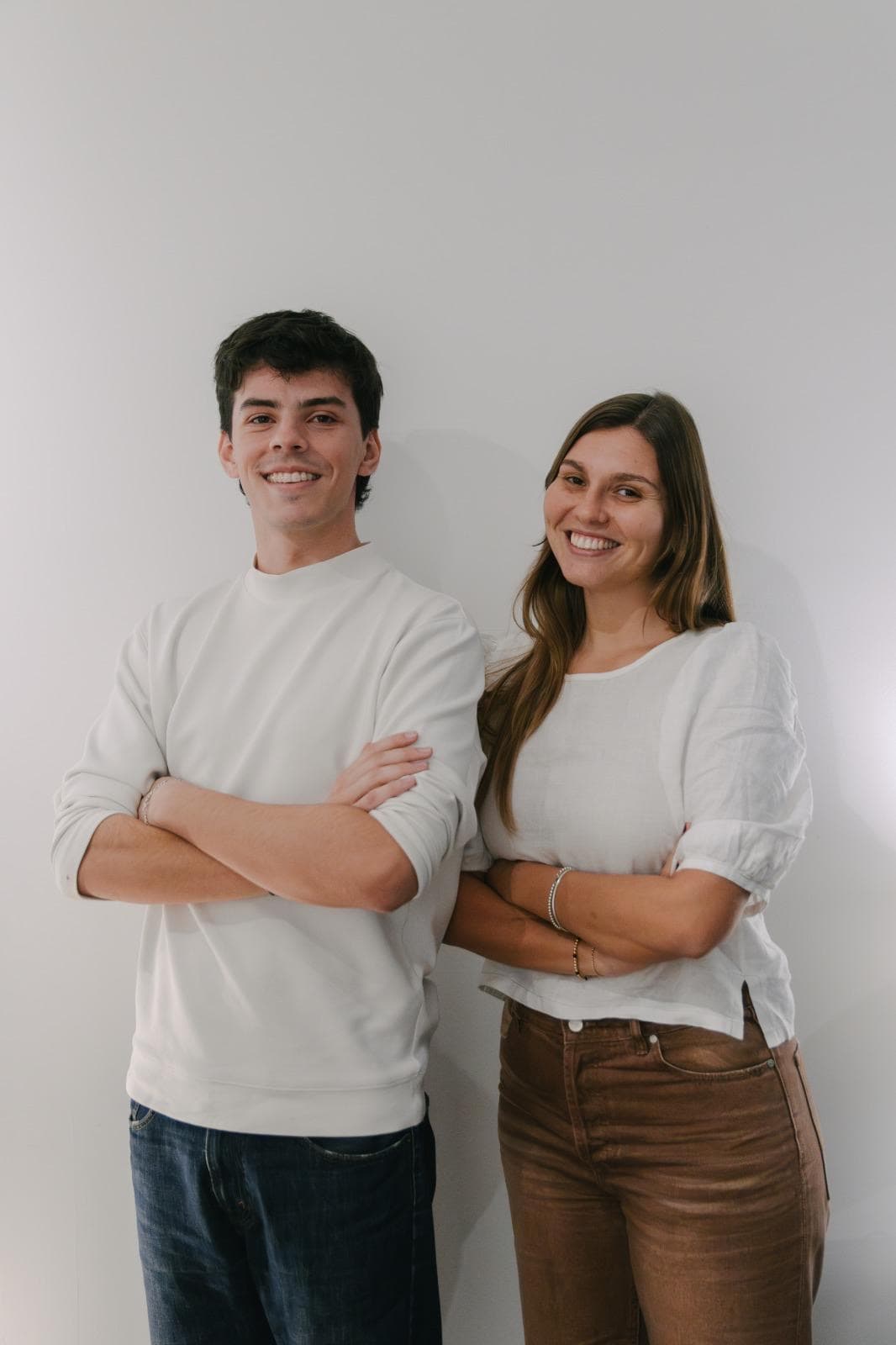 Micaela Beker y Tomás Consolandich, cofundadores de Pacto, con los brazos cruzados y sonriendo